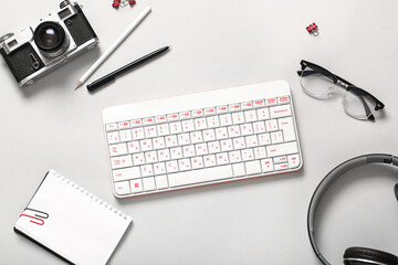 Composition with photo camera, headphones, glasses and keyboard on white background