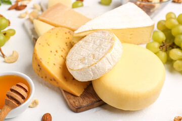 Board with different types of tasty cheese on light background