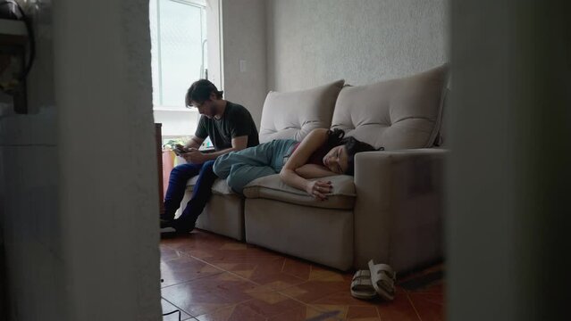 Young Couple in relationship turmoil: Man and woman in conflict  not making eye contact with each other. Female partner lying on couch ignoring boyfriend