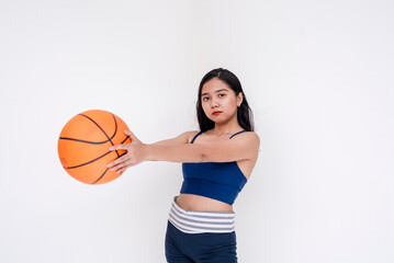 A sporty and athletic young woman posing while holding basketball on the side with both hands. Isolated on a white background.