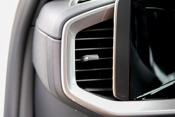 Close up modern heat vent inside car near car display screen.