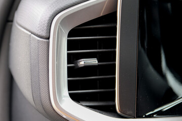Close up modern heat vent inside car near car display screen.