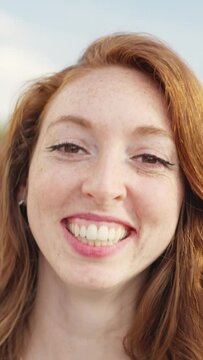 Red-haired woman looks at camera and smiles