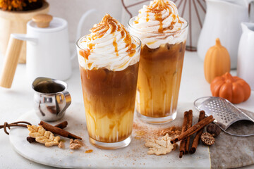 Iced pumpkin spice and caramel latte with whipped cream and syrup