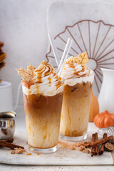 Iced pumpkin spice and caramel latte with whipped cream and syrup