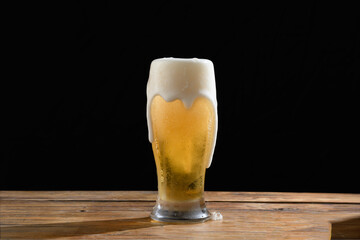 A glass of beer with a foamy head on a black background