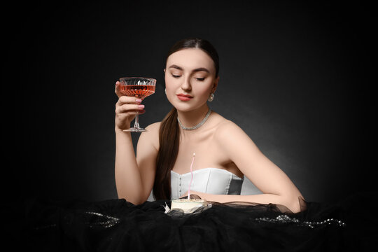 Fashionable photo of attractive woman with glass of wine and her Birthday cake on black background