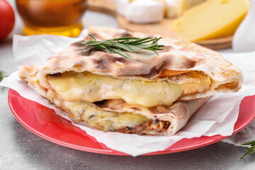 Tasty pizza calzones with cheese and rosemary on light grey table, closeup