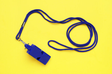 One blue whistle with cord on yellow background, top view
