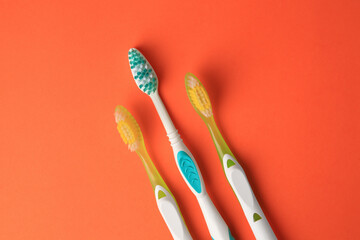 New toothbrushes on orange background, flat lay