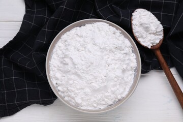 Bowl and spoon of starch on white wooden table, top view