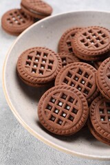 Tasty chocolate sandwich cookies with cream on light grey table, closeup