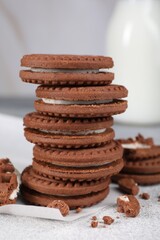Tasty chocolate sandwich cookies with cream on light grey table, closeup