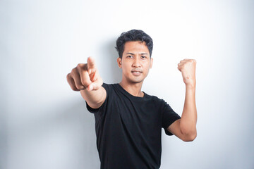 Fototapeta premium Asian young man in black t-shirt pointing forward, Looking at Camera, make choosing you gesture against white background