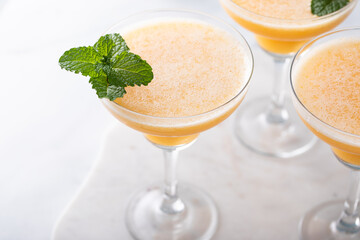 Frozen peach margaritas in three glasses with mint
