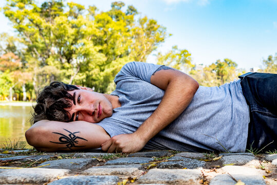 A young model man, lying on the ground while looking at camera