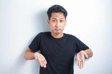 Shocked Asian man wearing black t-shirt pointing at the copy space down below him, isolated by...