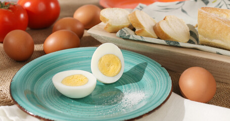 Halves of an egg on a plate. Boiled chicken eggs with bread and tomatoes. fresh eggs on the table. farm product closeup. natural healthy food. breakfast ingredients. rustic still life on a sunny day.