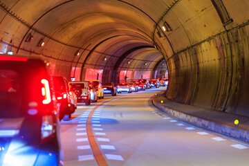 Line of cars stopped in heavy gridlock traffic in curved tunnel - 600277933