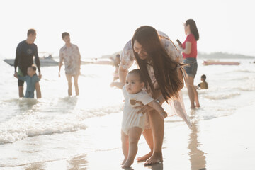 The picture of young woman practicing baby walking on the beach by the sea with the sunlight in the evening.