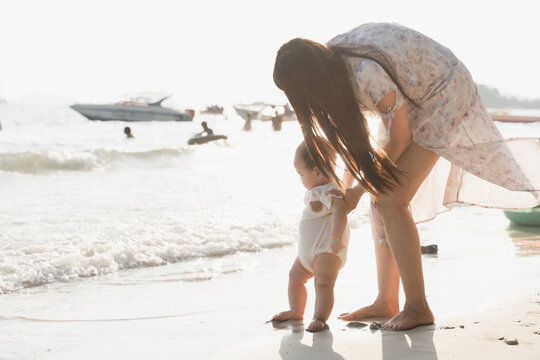 The picture of young woman practicing baby walking on the beach by the sea with the sunlight in the evening.