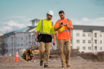 Builders on the job. Two builders in a hard hat at construction site. Men builders on construction sites. Hard hat builders helmet is a visible symbol of a safety and professionalism.