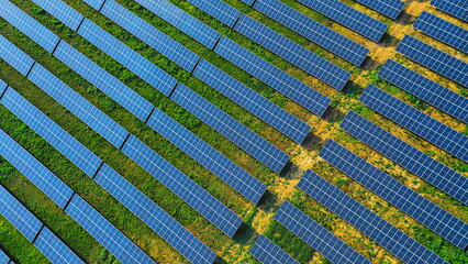Aerial view of a solar panel farm with rows of panels drawing energy from the sun at sunset. Rows of solar panels installed on a vast field. Ecology electrical innovation environment.