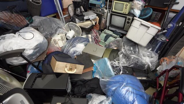 Hoarder house junk pile with bags of clothes, vintage electronics and storage boxes.  