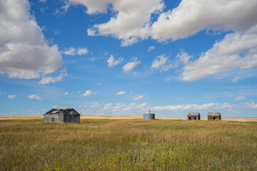 Obraz premium Abandond farm buildings sitting in the praire with a grain silo