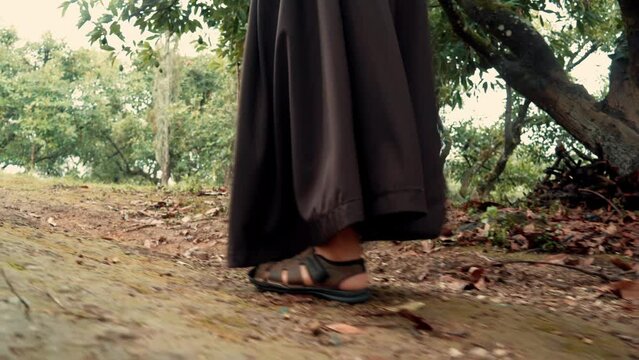 Fraile monje franciscano meditando subiendo y caminando por una montaña en un bosque al amanecer reflexionando por el camino al aire libre