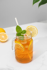 A glass of cold tea, ice cubes, lemon slices and a sprig of mint. Cooling summer drinks.