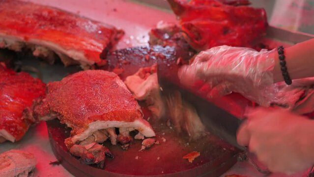 Chefs are cutting up charcoal-grilled roast pigs at a Chinese food stall
