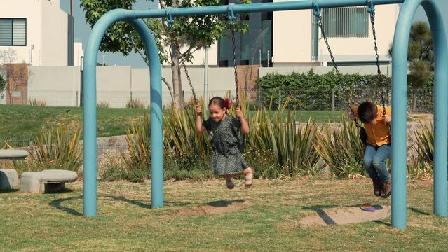 Niña feliz alegre contenta sonriente disfrutando y jugando en los columpios de un parque infantil al aire libre en un hermoso día soleado al aire libre viviendo su niñez y su infancia