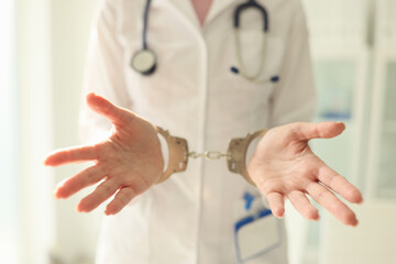 Doctor with stethoscope in handcuffs. Nurse with metal handcuffs on hands
