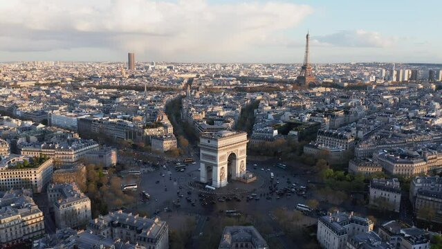 Aerial around Arc de Triumph, Paris city skyline, old town buildings, sunset light reflected on the street after rain