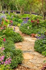 round wooden pathway winding in garden with flowers