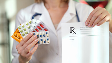 Woman doctor hand holding blank prescription paper and blisters of colourful pills