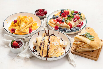 Sweet crepes assortment with berries chocolate on gray background. Homemade food concept. Top view, flat lay