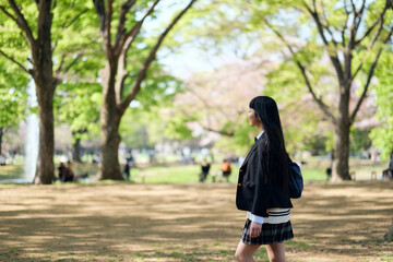 春の公園を散歩する女子高生のサイドショット