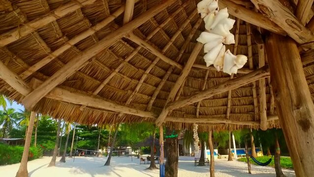 a line of shells hung on a straw parasol at jambiani beach zanzibar