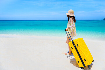 KOH LIPE, Asian women traveler holding yellow luggage walking on white sand at pattaya beach LIPE island, satun, near phuket, Thailand. Summer or travel trip concept.