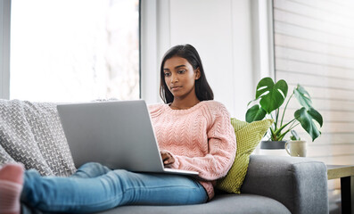 Relax, home and woman on a couch, laptop and typing with connection, search internet and online reading. Female person, pc and lady on a sofa, technology and chilling with a movie in the living room