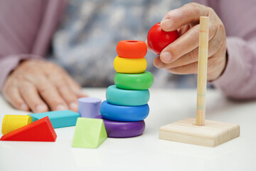 Fototapeta premium Asian elderly woman playing puzzles game to practice brain training for dementia prevention, Alzheimer disease..