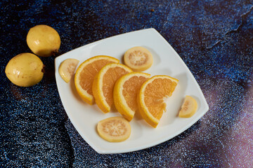 Plate of orange cut into segments, with guavas around it black Plate,