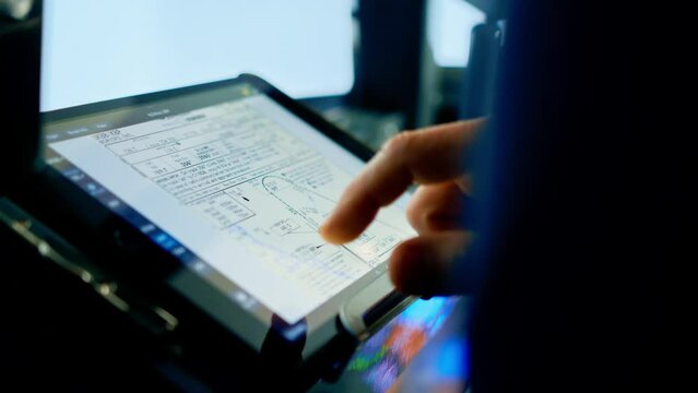 the pilot holds a tablet in his hands, looks at the flight route and chooses the landing place of the plane