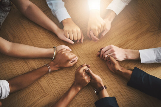 Support, diversity and people holding hands by a table at a group counseling or therapy session. Gratitude, trust and friends in a circle for praying together for religion, community and connection.