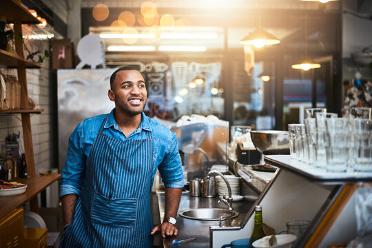 Coffee shop, barista and happy black man in restaurant for service, working and thinking in cafe. Small business owner, bistro startup and male entrepreneur smile in cafeteria counter ready to serve