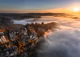 Wall murals Bastei Bridge Saxon, Germany - Aerial panoramic view of the Bastei on a foggy autumn morning with colorful autumn foliage and heavy fog under the rock. Bastei is a rock formation in Saxon Switzerland National Park