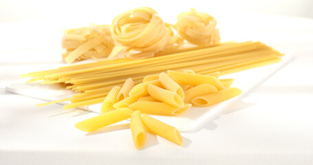 Raw Italian pasta fettuccine, spaghetti, fusilli, penne. traditional italian food close up. types of uncooked pasta on a white background. egg noodles. mediterranean cuisine.
