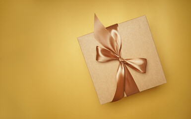 Square gift box. craft paper, yellow color bow knot, ribbons. paper background. empty label, sticker for text. Happy New Year package. top view